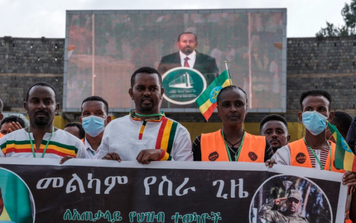 Orang-orang memegang spanduk saat PM Abiy memberikan pidato dalam upacara pelantikannya di Addis Ababa pada 4 Oktober. Foto: AFP.