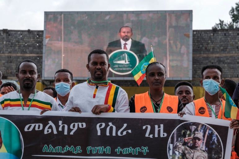 Orang-orang memegang spanduk saat PM Abiy memberikan pidato dalam upacara pelantikannya di Addis Ababa pada 4 Oktober. Foto: AFP.