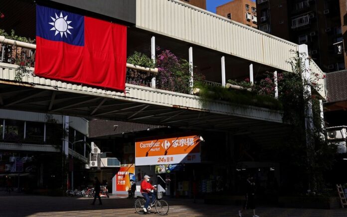 Seorang pria bersepeda melewati bendera Taiwan di Taipei, Taiwan, 16 November 2021. Foto: Reuters.