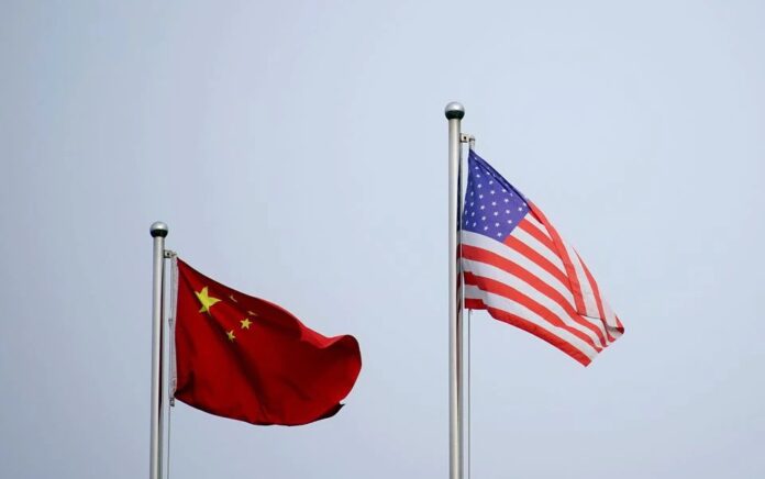 Bendera China dan AS berkibar di luar gedung perusahaan di Shanghai, China 14 April 2021. Foto: Reuters.