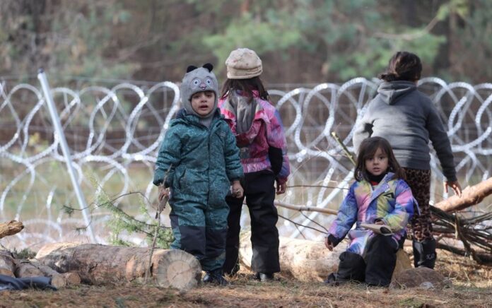 Anak-anak berkumpul di dekat pagar kawat berduri di kamp darurat migran di perbatasan Belarusia-Polandia di wilayah Grodno, Belarus 12 November 2021. Foto: Reuters.