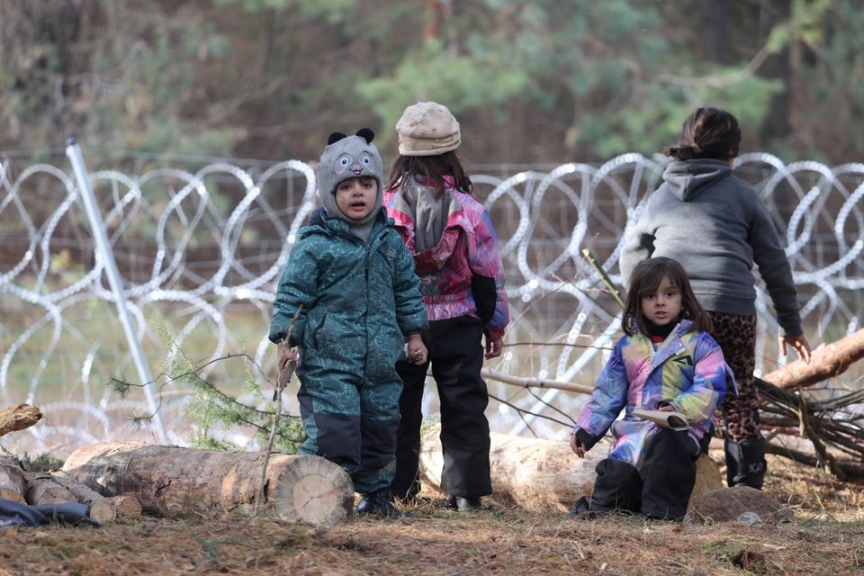 Anak-anak berkumpul di dekat pagar kawat berduri di kamp darurat migran di perbatasan Belarusia-Polandia di wilayah Grodno, Belarus 12 November 2021. Foto: Reuters.