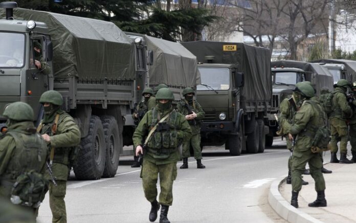 Prajurit bersenjata menunggu di dekat kendaraan tentara Rusia di luar pos penjaga perbatasan Ukraina di kota Balaclava, Krimea, 1 Maret 2014. Foto: Reuters.