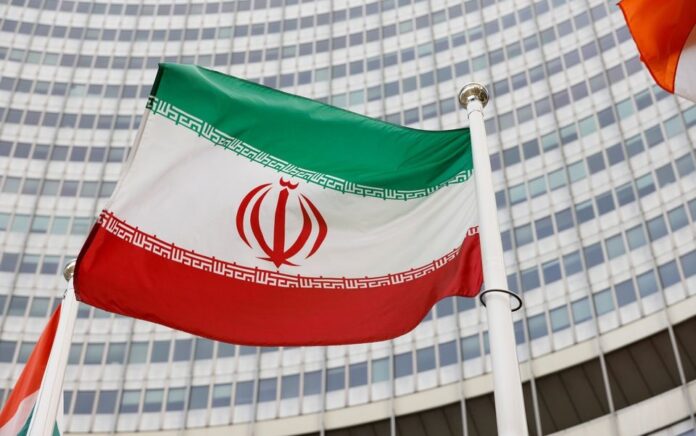 Bendera Iran melambai di depan markas Badan Energi Atom Internasional (IAEA), di tengah pandemi COVID-19, di Wina, Austria, 23 Mei 2021. Foto: Reuters.