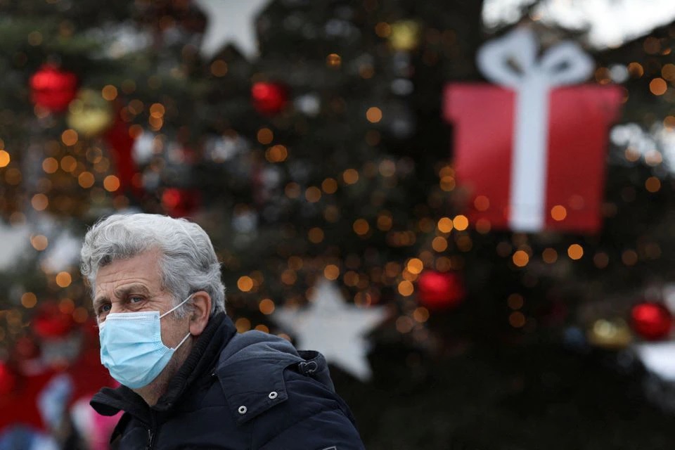Seseorang yang mengenakan masker pelindung melihat dekorasi Natal di Syntagma Square. Foto: Reuters.