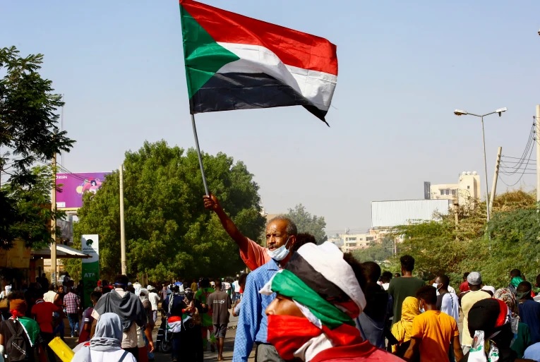 Seorang pengunjuk rasa mengibarkan bendera Sudan. Foto: Anadolu Agency.
