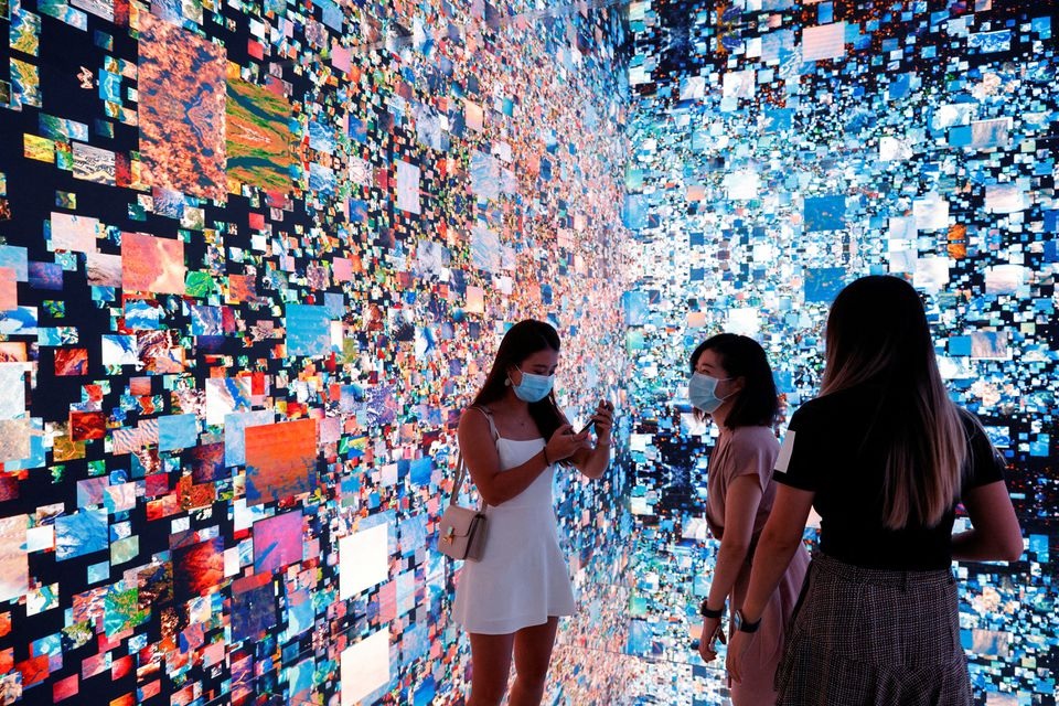 Pengunjung berfoto di depan instalasi seni imersif berjudul "Halusinasi Mesin — Ruang: Metaverse" oleh seniman media Refik Anadol, yang akan diubah menjadi NFT dan dilelang secara online di Sotheby's, di Digital Art Fair, di Hong Kong, China 30 September, 2021. Foto: Reuters.