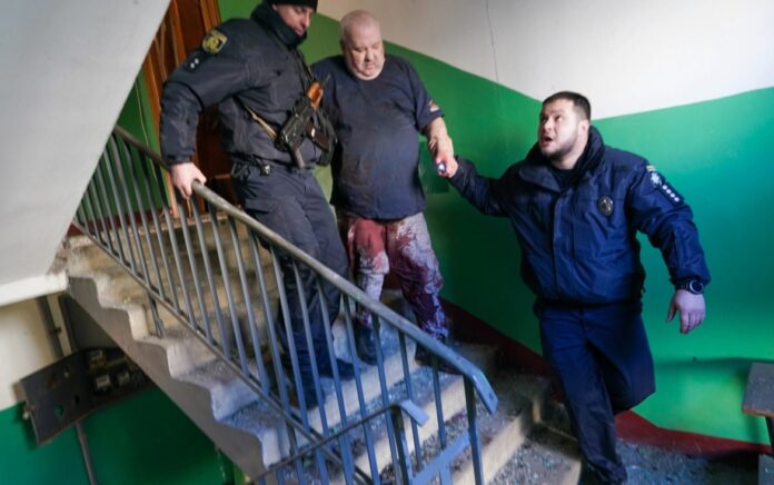 Pasukan keamanan Ukraina menemani seorang pria yang terluka setelah serangan udara menghantam sebuah kompleks apartemen di Chuhuiv, Kharkiv. Foto: Wolfgang Schwan/Anadolu Agency.