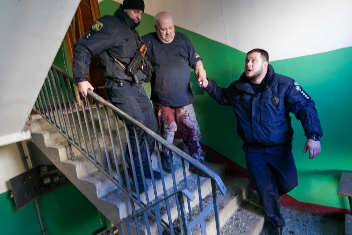 Pasukan keamanan Ukraina menemani seorang pria yang terluka setelah serangan udara menghantam sebuah kompleks apartemen di Chuhuiv, Kharkiv. Foto: Wolfgang Schwan/Anadolu Agency.