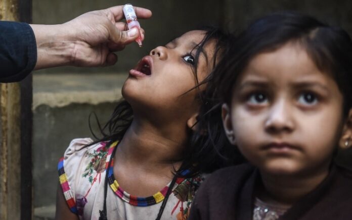 Seorang petugas kesehatan memberikan tetes vaksin polio kepada seorang gadis muda di Karachi, Pakistan, Januari 2022. Foto: AFP.