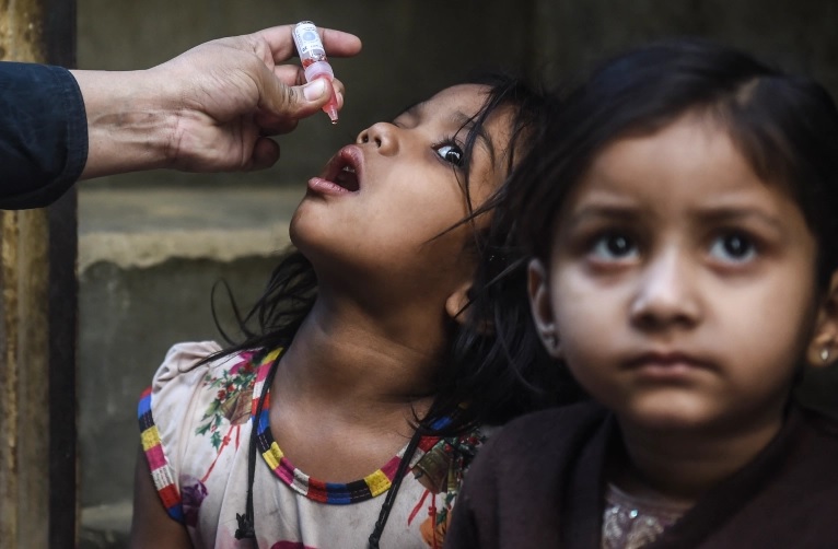 Seorang petugas kesehatan memberikan tetes vaksin polio kepada seorang gadis muda di Karachi, Pakistan, Januari 2022. Foto: AFP.