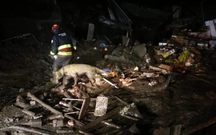 Orang-orang membersihkan puing-puing selama pencarian korban setelah tanah longsor yang disebabkan oleh hujan lebat di Quito pada Senin, 31 Januari 2022. Foto: API/AFP.