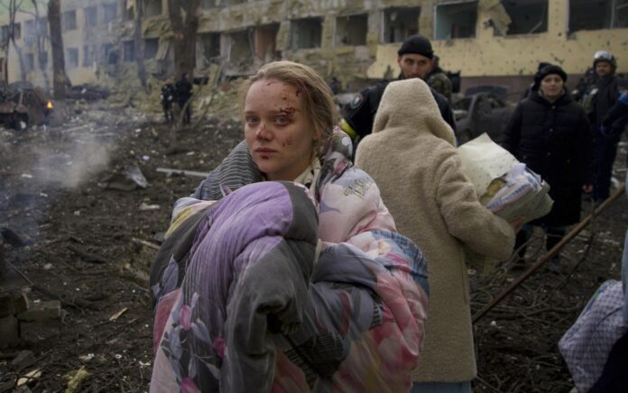 Mariana Vishegirskaya berdiri di luar rumah sakit bersalin yang rusak akibat penembakan di Mariupol, Ukraina, Rabu, 9 Maret 2022. Visheirskaya dibawa ke rumah sakit terdekat lainnya di mana ia melahirkan bayi perempuan yang diberi nama Veronika keesokan harinya. Foto: AP Photo/Mstyslav Chernov.