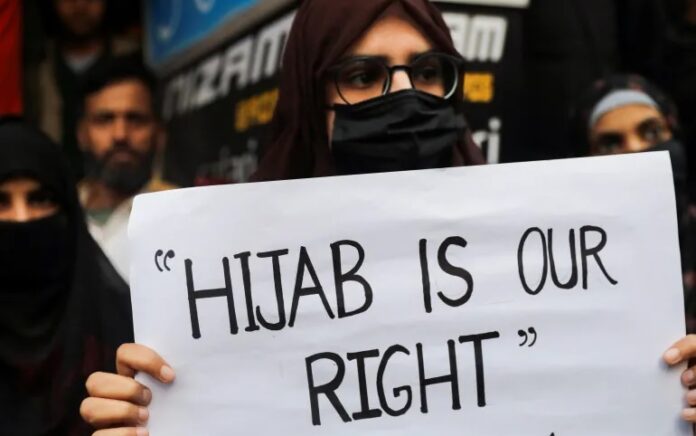 Seorang wanita Muslim di Shaheen Bagh, New Delhi, memegang spanduk saat dia memprotes larangan jilbab di perguruan tinggi di negara bagian Karnataka. Foto: Anushree Fadnavis/Reuters.