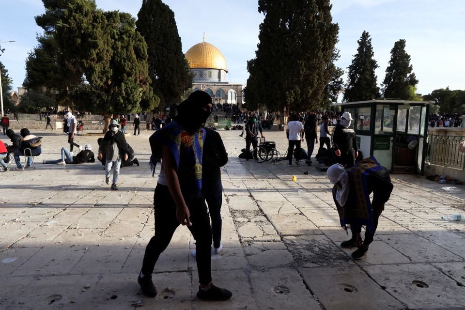 Para pengunjuk rasa Palestina berjalan di sekitar selama bentrokan dengan pasukan keamanan Israel di kompleks Masjid Al-Aqsa, di Kota Tua Yerusalem 22 April 2022. Foto: Reuters/Ammar Awad.