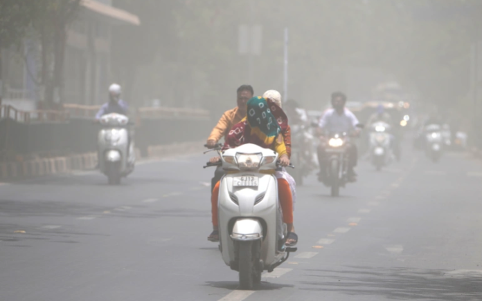 Seorang wanita menutupi wajahnya dengan syal untuk melindungi dari gelombang panas perjalanan melalui badai debu di Ahmedabad, India, Sabtu, 21 Mei 2022. Foto: Ajit Solanki/AP.