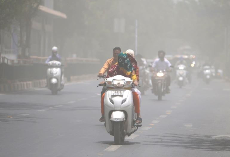 Seorang wanita menutupi wajahnya dengan syal untuk melindungi dari gelombang panas perjalanan melalui badai debu di Ahmedabad, India, Sabtu, 21 Mei 2022. Foto: Ajit Solanki/AP.