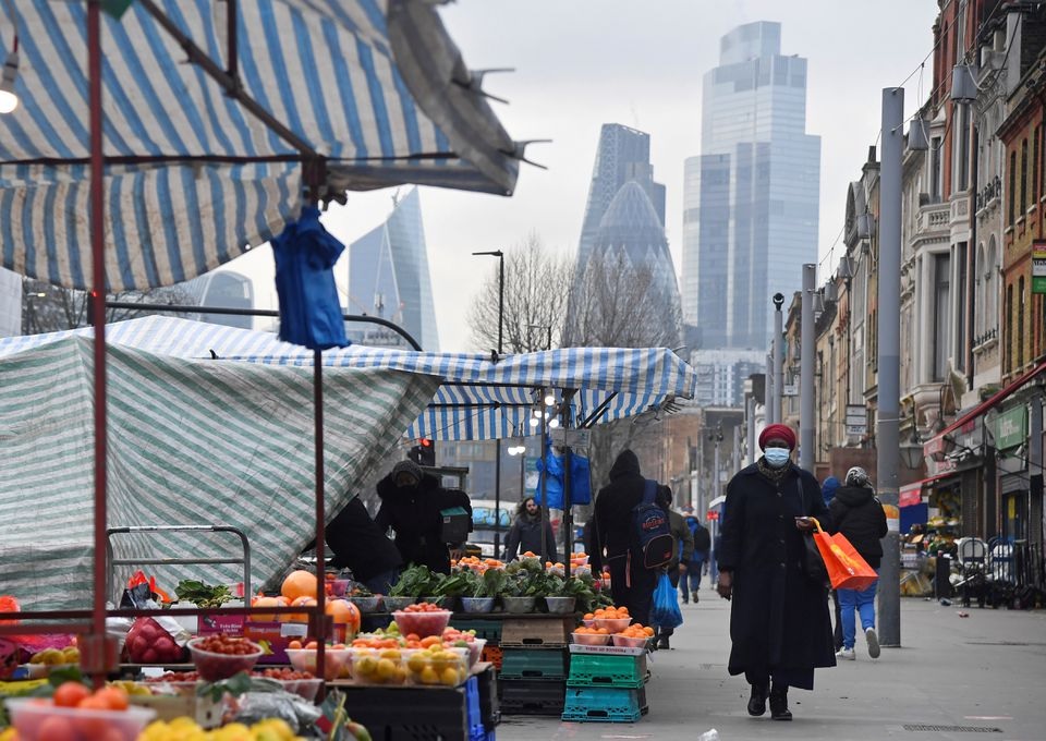 Orang-orang berbelanja di kios-kios pasar, dengan gedung pencakar langit distrik keuangan CIty of London terlihat di belakang, di London, Inggris, 15 Januari 2021. Foto: Reuters/Toby Melville.