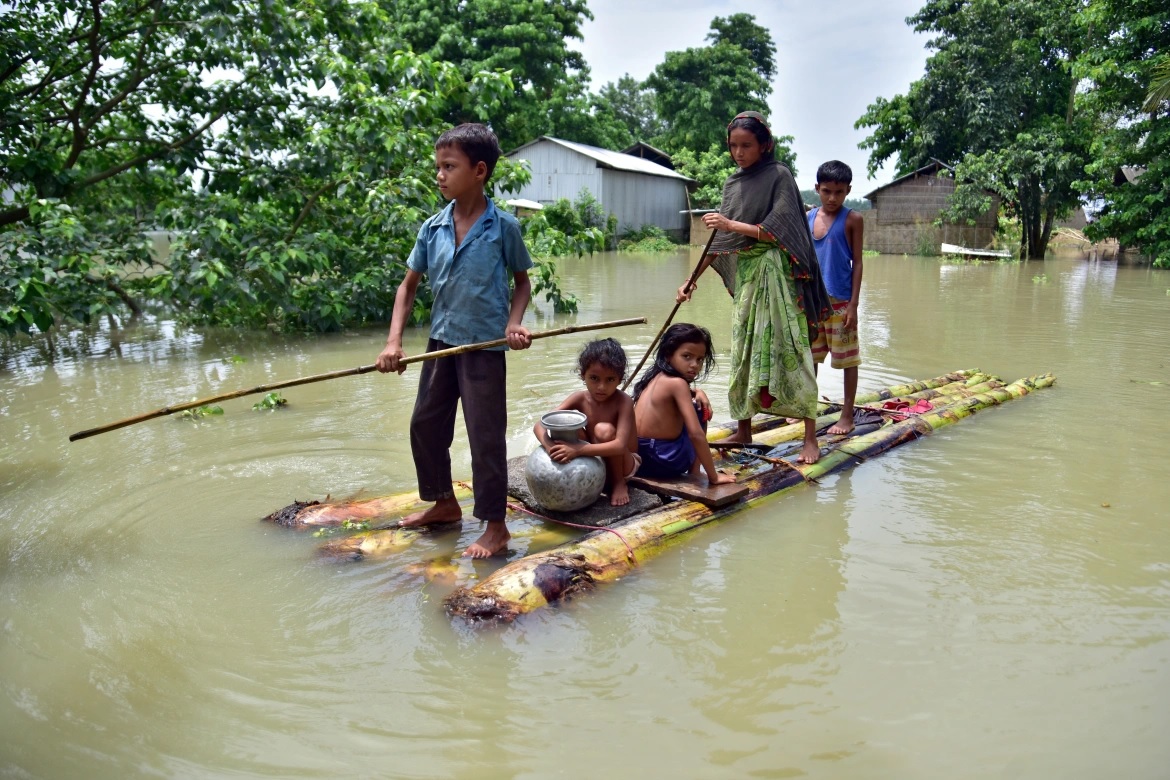 Penduduk desa mendayung rakit darurat melalui ladang banjir untuk mencapai tempat yang lebih aman di desa Mayong yang terkena dampak banjir di distrik Morigaon, di negara bagian timur laut Assam, India. Foto: Anuwar Hazarika/Reuters.