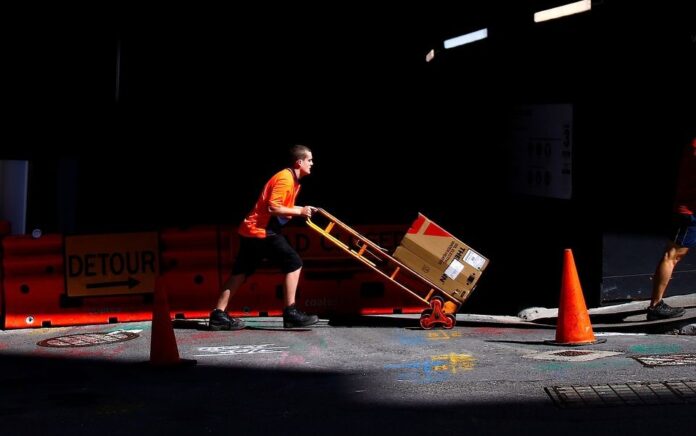 Seorang pekerja mendorong troli berisi barang melewati lokasi konstruksi di kawasan pusat bisnis (CBD) Sydney di Australia, 15 Maret 2018. Foto: Reuters/David Gray.