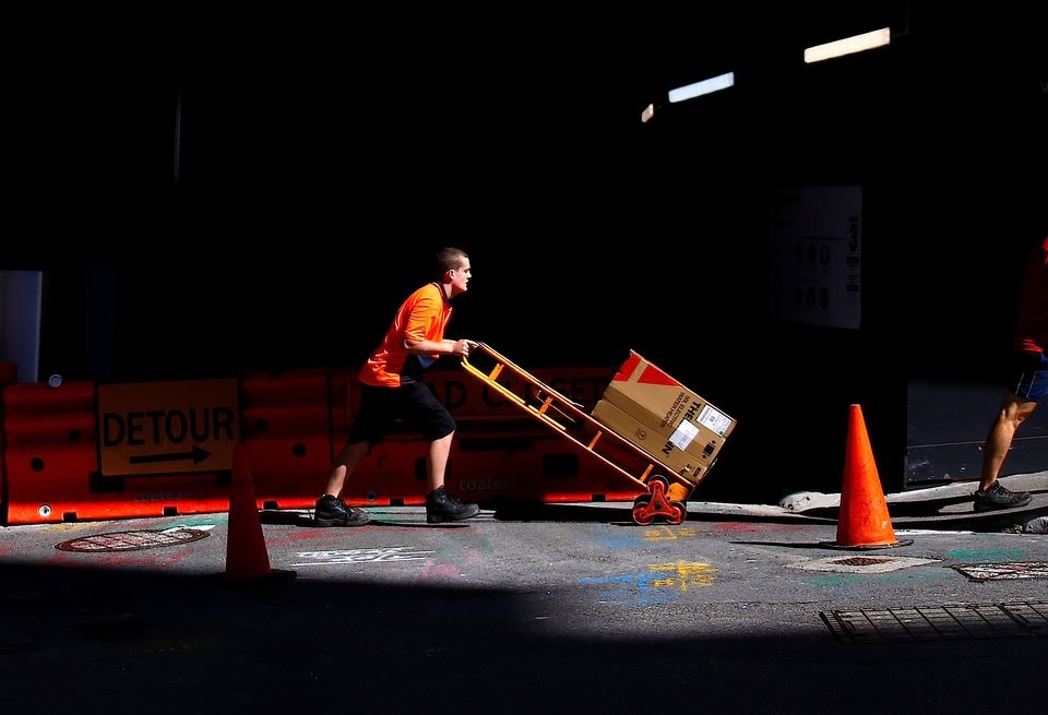 Seorang pekerja mendorong troli berisi barang melewati lokasi konstruksi di kawasan pusat bisnis (CBD) Sydney di Australia, 15 Maret 2018. Foto: Reuters/David Gray.