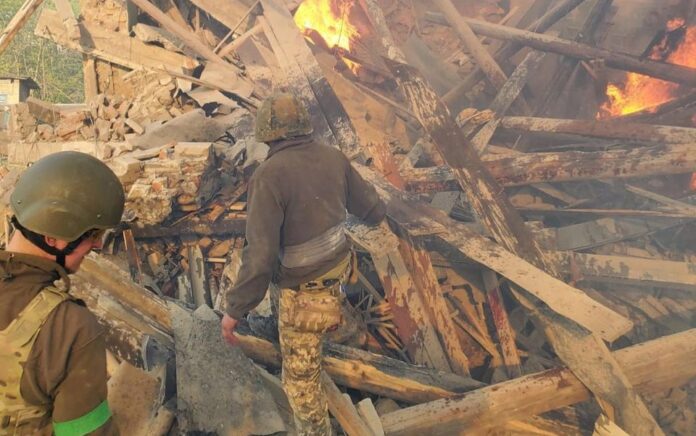 Awak darurat bekerja di dekat puing-puing yang terbakar, setelah sebuah gedung sekolah terkena akibat penembakan, di desa Bilohorivka, Luhansk, Ukraina, 8 Mei 2022. Foto: Layanan Darurat Negara/Handout via Reuters.