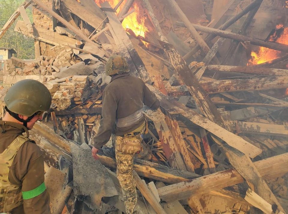 Awak darurat bekerja di dekat puing-puing yang terbakar, setelah sebuah gedung sekolah terkena akibat penembakan, di desa Bilohorivka, Luhansk, Ukraina, 8 Mei 2022. Foto: Layanan Darurat Negara/Handout via Reuters.
