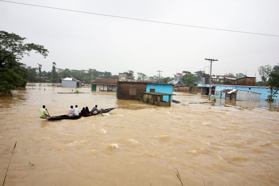 Orang-orang memindahkan perahu di daerah banjir saat banjir meluas di bagian timur laut negara itu, di Sylhet, Bangladesh, 19 Juni 2022. Foto: Reuters/Stringer.
