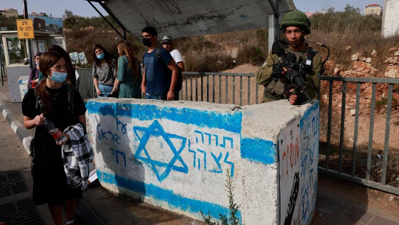 Seorang tentara Israel berjaga di stasiun bus dekat pemukiman Israel Ariel di Tepi Barat yang diduduki, pada 14 Oktober 2021. Foto: AFP.