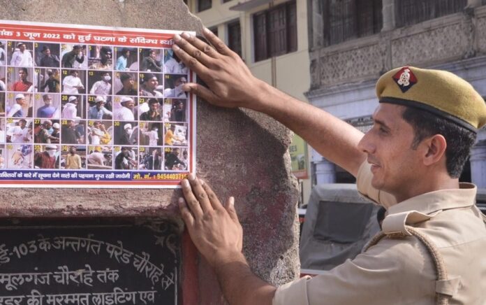 Seorang polisi menempelkan poster tersangka kekerasan komunal di Kanpur, Senin, 6 Juni 2022. Foto: PTI.