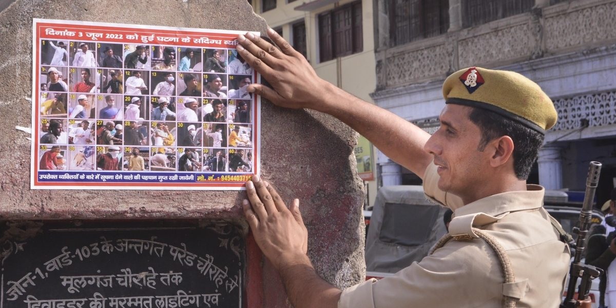 Seorang polisi menempelkan poster tersangka kekerasan komunal di Kanpur, Senin, 6 Juni 2022. Foto: PTI.