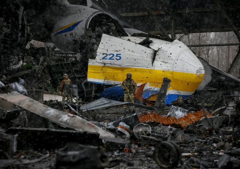 Seorang anggota layanan Ukraina berjalan di depan pesawat kargo Antonov An-225 Mriya, pesawat terbesar di dunia, dihancurkan oleh pasukan Rusia, di sebuah lapangan terbang di pemukiman Hostomel, di wilayah Kyiv, Ukraina 3 April. Foto: Reuters/Gleb Garanich.