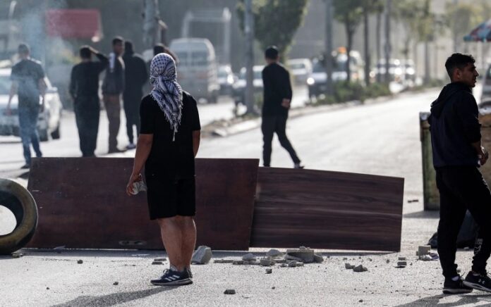 Warga Palestina menghadapi pasukan Israel di pintu masuk kamp pengungsi Nur Shams di Tepi Barat yang diduduki. Foto: Jaafar Ashtiyeh/AFP.