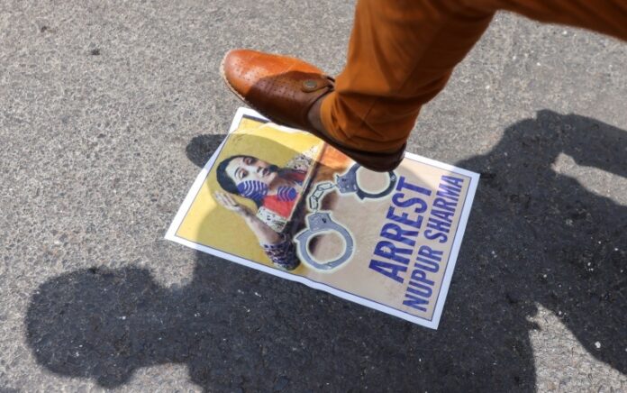 Seorang demonstran di Mumbai menginjak poster anggota BJP Nupur Sharma selama protes setelah komentarnya tentang Nabi Muhammad. Foto: Francis Mascarenhas/Reuters.