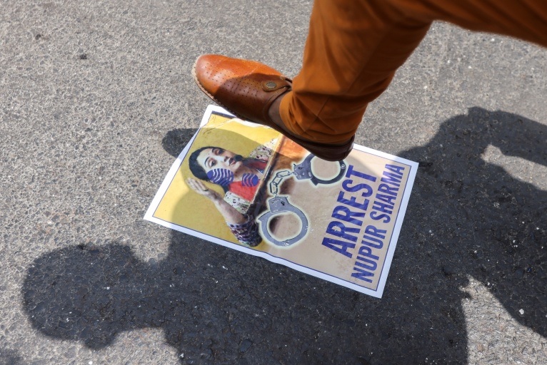 Seorang demonstran di Mumbai menginjak poster anggota BJP Nupur Sharma selama protes setelah komentarnya tentang Nabi Muhammad. Foto: Francis Mascarenhas/Reuters.