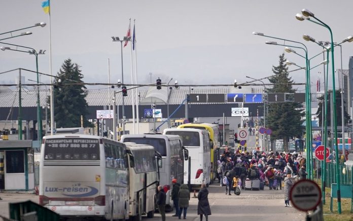 Pengungsi Ukraina yang melarikan diri dari invasi Rusia mengantri di perbatasan untuk masuk ke Polandia, di Shehyni, Ukraina, 27 Februari 2022. Foto: Reuters/Bryan Woolston.