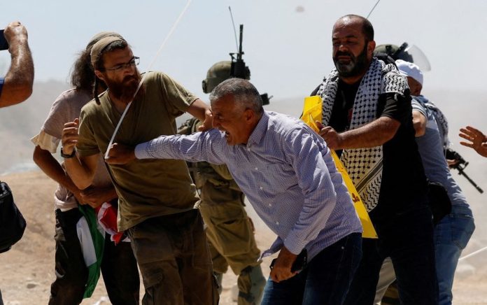 Pengunjuk rasa Palestina bentrok dengan pemukim Israel selama protes terhadap aktivitas pemukiman Israel di desa Al Mughayyir, di Tepi Barat yang diduduki Israel 29 Juli 2022. Foto: Reuters/Mohamad Torokman.