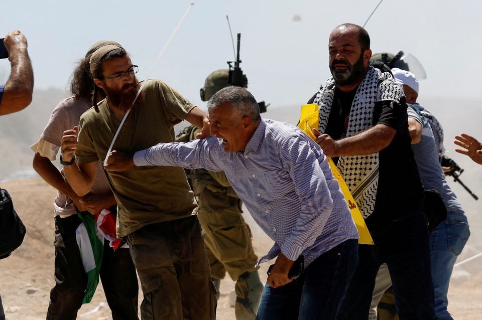 Pengunjuk rasa Palestina bentrok dengan pemukim Israel selama protes terhadap aktivitas pemukiman Israel di desa Al Mughayyir, di Tepi Barat yang diduduki Israel 29 Juli 2022. Foto: Reuters/Mohamad Torokman.