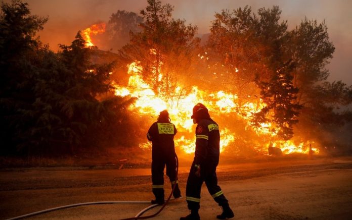 Petugas pemadam kebakaran berusaha memadamkan api yang berkobar di Ntrafi, Athena, Yunani, 19 Juli 2022. Foto: Reuters/Costas Baltas.