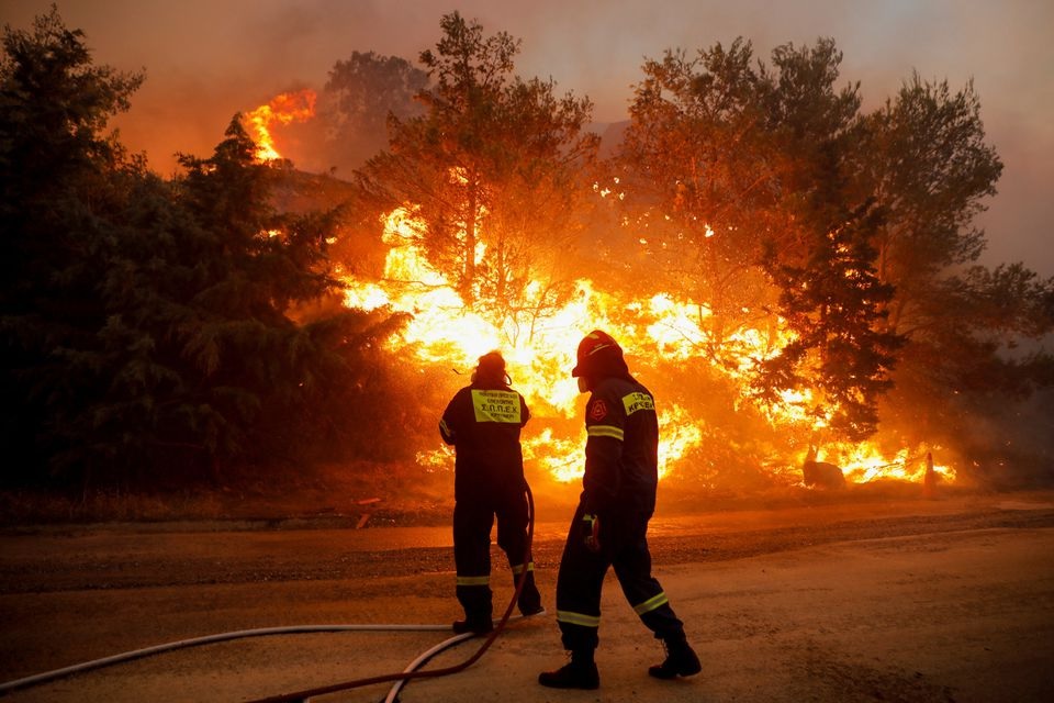 Petugas pemadam kebakaran berusaha memadamkan api yang berkobar di Ntrafi, Athena, Yunani, 19 Juli 2022. Foto: Reuters/Costas Baltas.