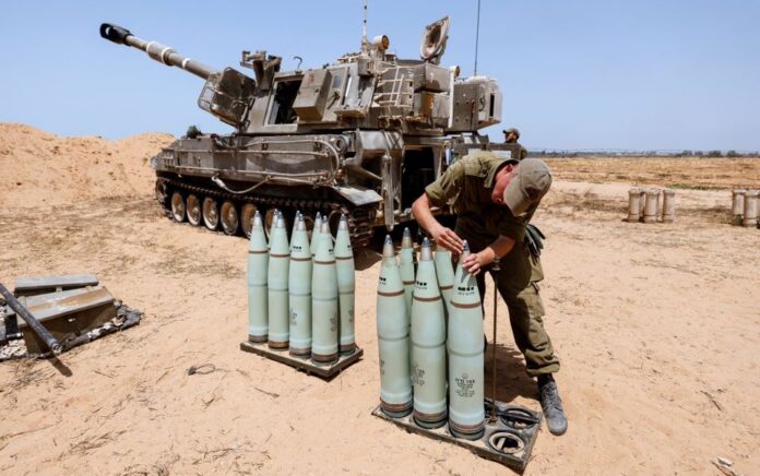 Seorang tentara Israel memeriksa amunisi di sebelah unit artileri bergerak di sebuah lapangan di sisi perbatasan Israel dengan Jalur Gaza 6 Agustus 2022. Foto: Reuters/Amir Cohen.