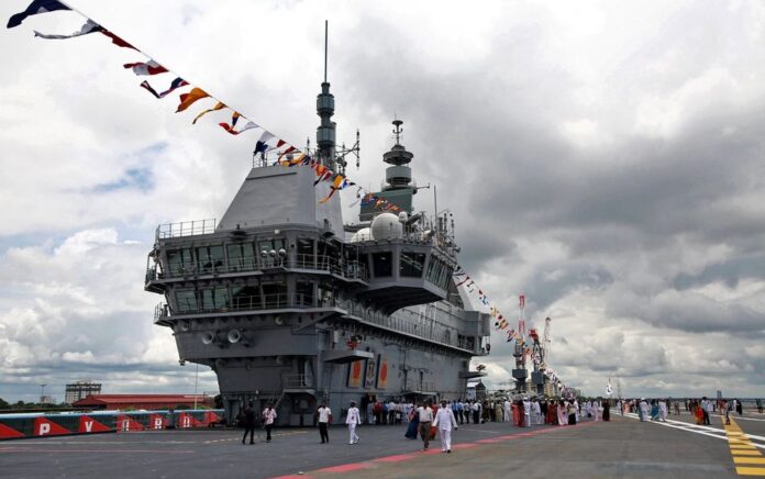 Perwira Angkatan Laut India dan awak media berjalan di dek penerbangan kapal induk buatan India pertama INS Vikrant setelah upacara peresmian di galangan kapal milik negara di Kochi, India, 2 September 2022. Foto: Reuters/Sivaram V.