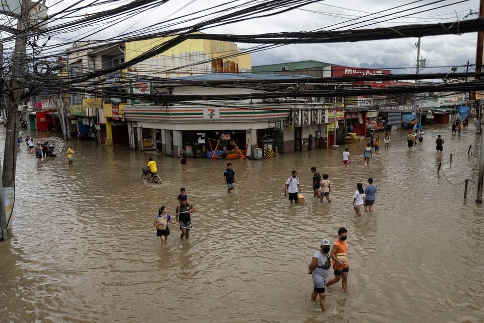 Orang-orang mengarungi jalan yang terendam banjir menyusul hujan lebat badai tropis Nalgae, di Imus, provinsi Cavite, Filipina, 30 Oktober 2022. Foto: Reuters/Eloisa Lopez.