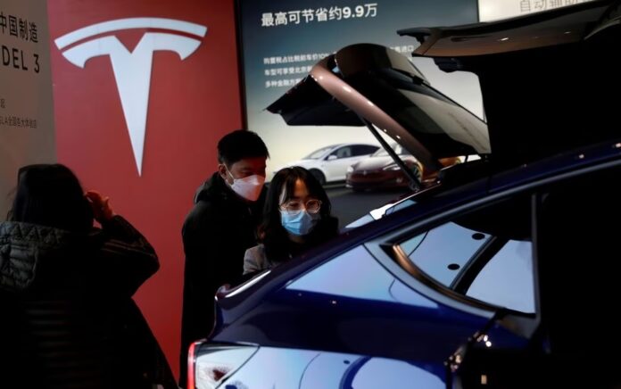 Pengunjung yang memakai masker melihat mobil sport utility vehicle (SUV) Tesla Model Y buatan China di showroom pembuat kendaraan listrik di Beijing, China 5 Januari 2021. Foto: Reuters/Tingshu Wang.