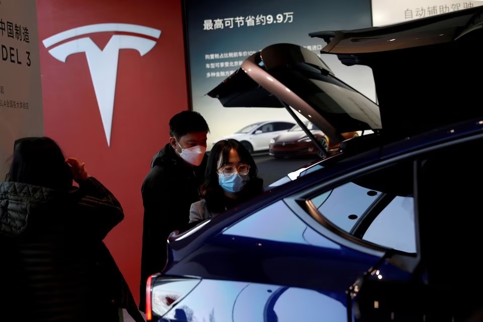 Pengunjung yang memakai masker melihat mobil sport utility vehicle (SUV) Tesla Model Y buatan China di showroom pembuat kendaraan listrik di Beijing, China 5 Januari 2021. Foto: Reuters/Tingshu Wang.