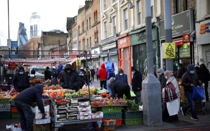 Orang-orang berbelanja di sebuah kios pasar di London timur, Inggris, 23 Januari 2021. Foto: Reuters/Henry Nicholls.