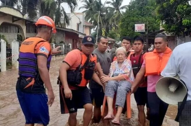 Petugas penyelamat membantu warga yang terkena banjir di Plaridel, Misamis Occidental Province, Filipina, pada 26 Desember 2022. Foto: Philippine Coast Guard/Reuters.