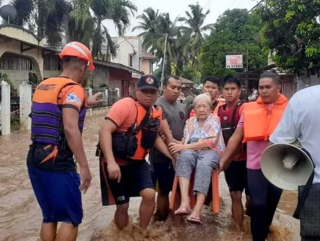 Petugas penyelamat membantu warga yang terkena banjir di Plaridel, Misamis Occidental Province, Filipina, pada 26 Desember 2022. Foto: Philippine Coast Guard/Reuters.