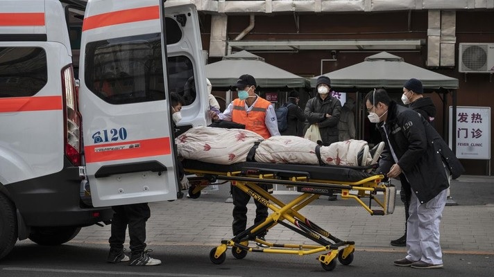 Pengemudi ambulans menurunkan pasien di luar klinik demam yang merawat pasien COVID-19 di Beijing, China, Rabu (21/12/2022). Kondisi pandemi Covid-19 di China terus memburuk seiring dengan berakhirnya kebijakan penguncian ketat di seluruh negeri. (Photo by Kevin Frayer/Getty Images)