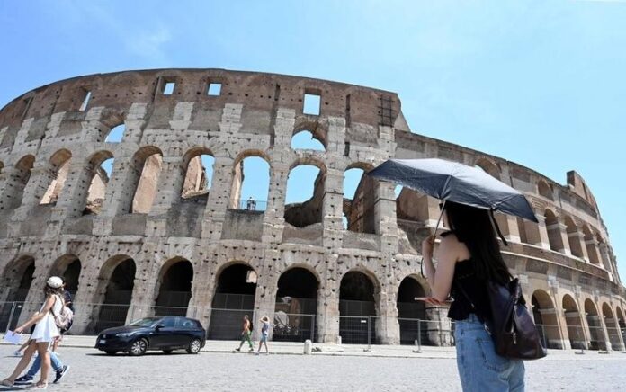 Seorang wanita berlindung dari sinar matahari menggunakan payung di tengah cuaca panas di Colosseum di Roma, Italia, pada 17 Juni 2022. (Xinhua/Alberto Lingria)